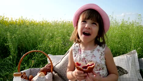 female-child-in-panama-with-bun-on-nature,-Weekend-at-picnic,-Girl-on-flower-meadow-with-pastries-and-milk,-Happy-joyful-child