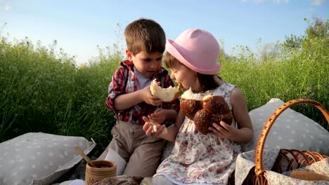 junge-füttert-Mädchen-mit-Backware,-niedliche-kleine-Kinder-teilen-Brot,-Produkte-in-Picknick-Baske,-Kinder,-die-Spaß-an-der-frischen-Luft