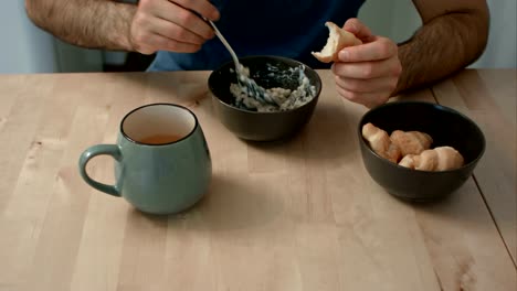Man-eating-porridge-and-croissants-for-breakfast