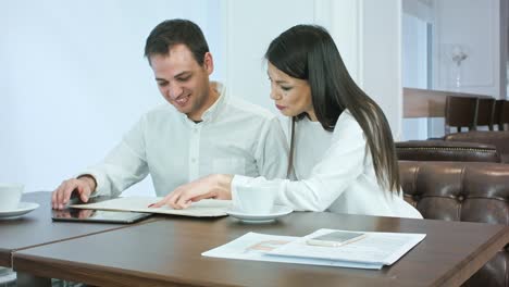 Couple-of-office-workers-looking-at-menu-and-deciding-what-to-order-at-a-coffee-shop