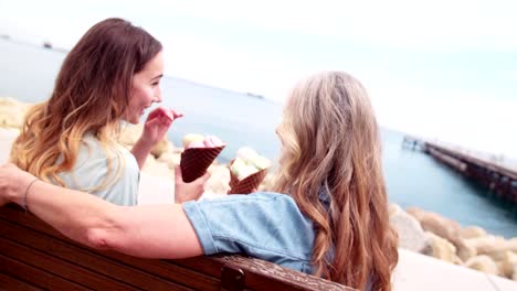 Hermosa-abuela-y-nieta-comiendo-helado-por-el-mar