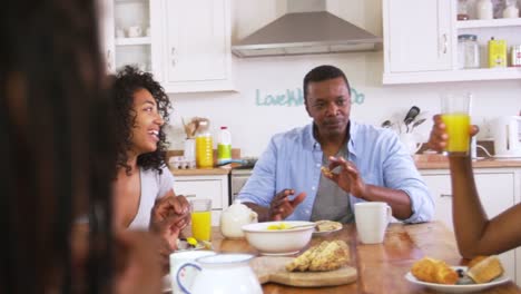 Family-With-Teenage-Children-Eating-Breakfast-In-Kitchen