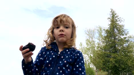 Kleine-Mädchen-essen-einen-Brownie-und-spielen-mit-einem-Spielzeug-Schwert