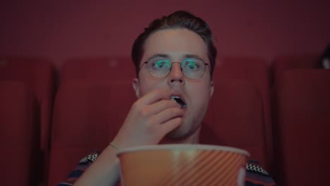 eine-junge-Hipster-Popcorn-zu-essen,-während-gerade-die-Premiere-von-einem-Kinofilm-und-eine-TV-Serie-eine-Seifenoper