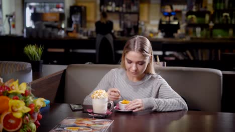 Una-mujer-joven-y-bonita-comer-postre-y-beber-leche-frapes-con-sabor-a-caramelo,-una-señora-le-encanta-trabajar-ella-misma-con-deliciosos-platos-en-una-cafetería