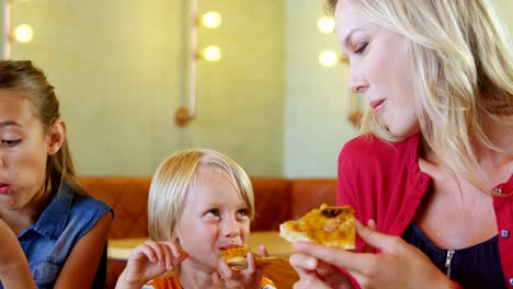 Madre-y-niños-pizza-en-restaurante-4k