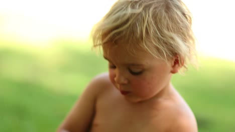 Candid-4k-resolution-clip-of-infant-child-eating-pear-fruit-outdoors-in-the-sunlight.-Candid-shot-of-blonde-baby-boy-eating-healthy-fruit