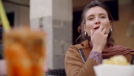 Woman-talking-french-fries-during-cocktail-aperitif-outside-of-cafe.Medium-shot.-Caucasian-couple-in-love-roadtrip-vacation-italian-travel