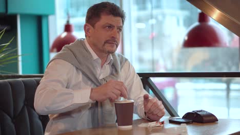 Man-mature-in-a-white-shirt-with-sweater-stirs-sugar-with-a-stick-in-the-freshly-made-morning-coffee