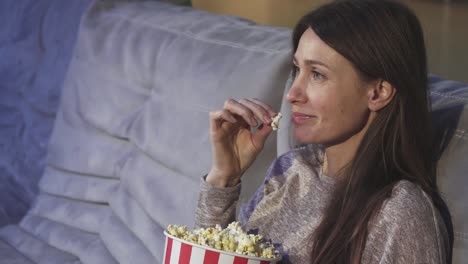 Close-up-of-a-mature-woman-eating-popcorn-smiling-at-the-cinema