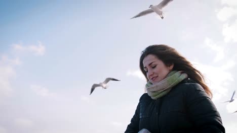 Mujer-joven-alimentando-gaviotas-en-invierno-cerca-del-mar,-cámara-lenta