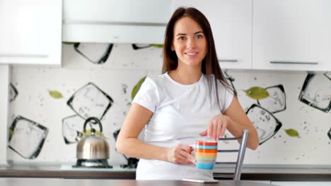 Sonriente-a-mujer-joven-con-taza-de-té-en-la-cocina