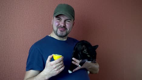 Ein-Mann-mit-einer-Katze-in-seiner-Hand-eine-Zitrone-Essen