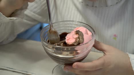 Das-kleine-Mädchen-mischt-sich-Schokolade-und-Erdbeer-Eis-in-eine-Tasse.