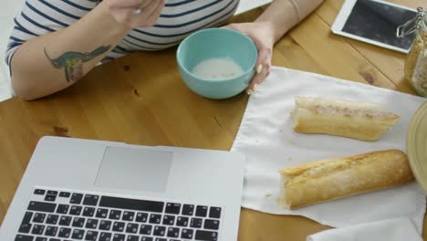 Mujer-que-trabaja-en-la-computadora-portátil-mientras-desayuno-comer