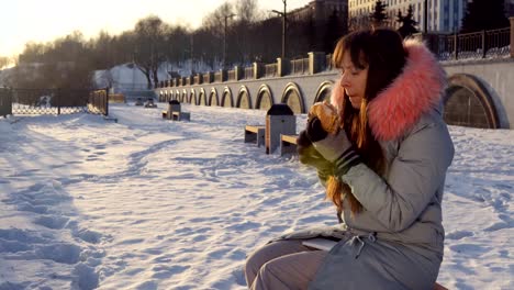 Junge-Frau-isst-einen-Burger-auf-Winter-Straße