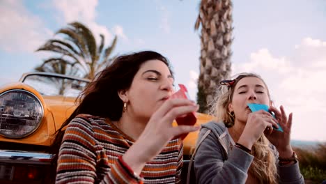 Young-women-on-road-trip-eating-candy-and-having-fun