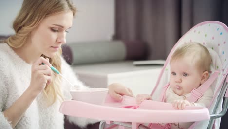 Beautiful-woman-feeding-baby-in-chair.-Mom-feeding-child-with-pureed-food