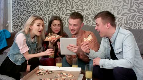 Gruppe-von-Freunden-essen-Pizza-zum-Mitnehmen-und-Programm-auf-Tablet-ansehen