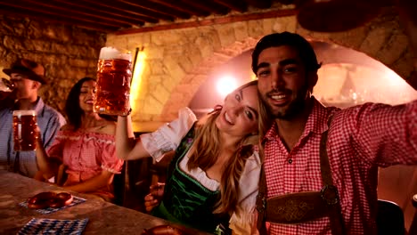 Pareja-joven/esposos-celebrar-Oktoberfest-con-cerveza-y-pretzels-en-el-bar