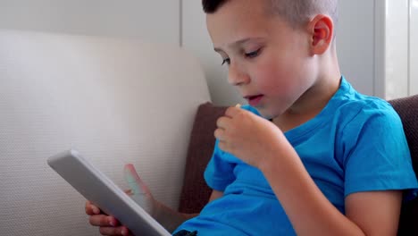 Cute-boy-eating-corn-flakes-while-playing-on-tablet