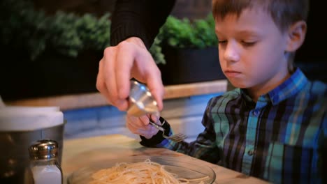 Boy-looks-how-dad-pours-the-spaghetti-with-oil-butter.