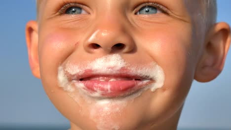 Hungrige-junge-essen-Eis-am-Strand-des-Meeres.-Das-Gesicht-des-Babys-ist-mit-Eiscreme-verschmiert.