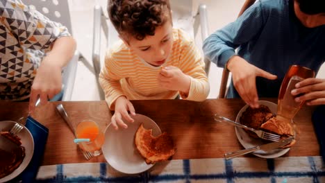 Niños-sentados-a-la-mesa-de-la-cocina-y-desayunando-juntos