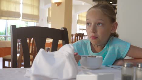 Chica-adolescente-de-retrato-comer-gachas-de-avena-en-el-desayuno-de-la-mañana-en-el-restaurante-del-hotel