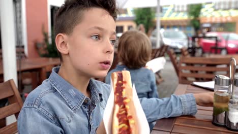 8-Jahre-alter-Junge-in-Jeanshemd-Essen-Leckere-Hot-Dog.