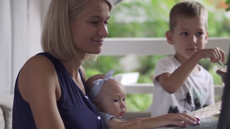 Mujer-con-los-niños-funciona-en-laptop-en-café