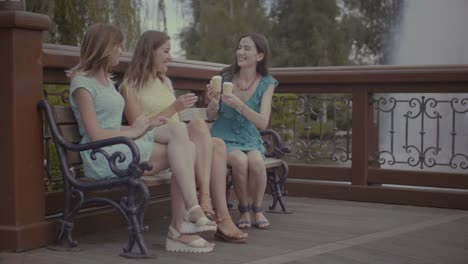 Three-beautiful-girlfriends-eating-ice-cream-on-bench