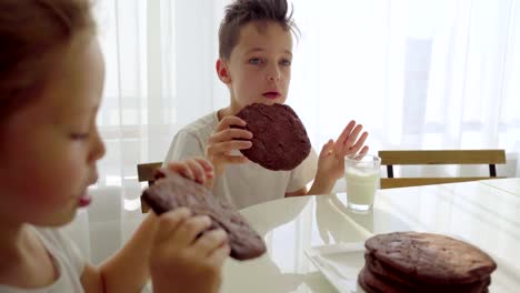 Two-boy-eating-homemade-chocolate-cookies-with-milk-at-kitchen