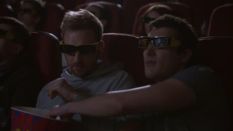 Man-eating-popcorn-in-3d-cinema.-Spectactors-enjoy-cinema-snacks