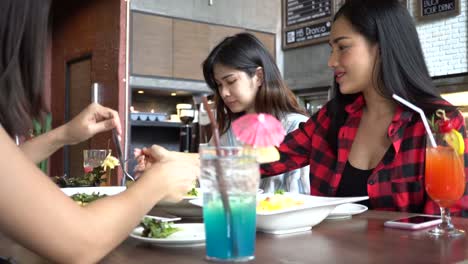 Group-of-Four-young-Asian-people,-one-man,-three-women,-eating-and-talking-at-cafe-and-restaurant.-Friendship-concept