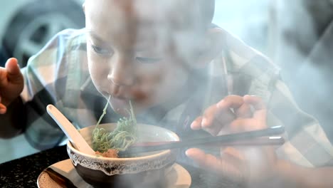 happy-child-eating-delicious-noodle-in-restaurant.-Asian-boys-who-have-vision-disabilities.-Left-eye-is-not-visible-from-brain-surgery.-Come-back-to-normal-life-Effect-of-the-treatment.-New-life