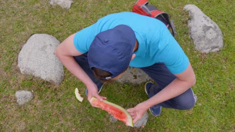 Man-eating-slice-of-sweet-juicy-watermelon-and-smiling-outdoors,-high-angle-view