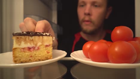 Tomate-cocktail-o-pastel.-Una-difícil-elección-de-alimentos-saludables-de-la-nevera,-dentro-de-vista,-hombre-fuera-de-foco