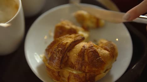 Nahaufnahme---schneidet-die-Hand-einer-unbekannten-Frau-eine-Croissant-mit-Dessert-Messer