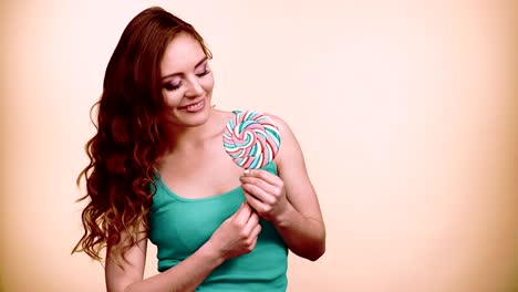 Woman-smiling-girl-with-lollipop-candy-on-green-4K