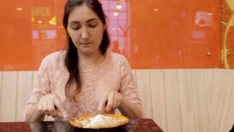 Pretty-girl-eats-a-pancake-with-ice-cream-in-cafe,-close-up