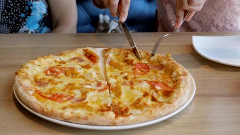 Women-in-a-cafe-lay-out-slices-of-pizza-on-plates