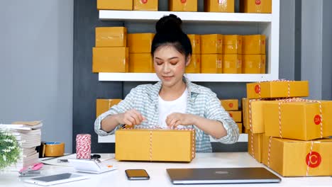 junge-Unternehmerin-sind-Seile-binden-und-Verpackung-von-Produkten-in-Paketbox,-vorbereiten-für-die-Auslieferung-an-Kunden-im-home-office