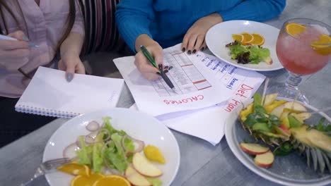 mujer-con-calendario-de-planificación-de-la-dieta-de-adelgazamiento-contar-calorías-en-hoja-de-papel-durante-el-tiempo-de-la-comida-sana