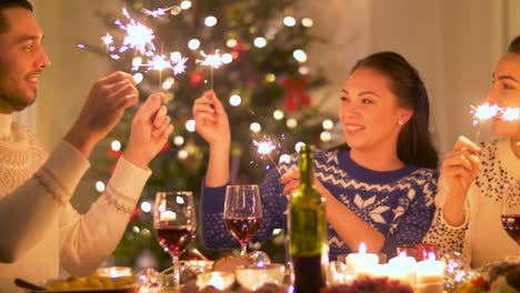 happy-friends-with-sparklers-having-christmas-dinner-at-home