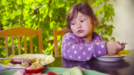 Dos-chicas-traviesas-están-sentado-en-la-mesa-y-comer-pasta-y-salchicha-frita