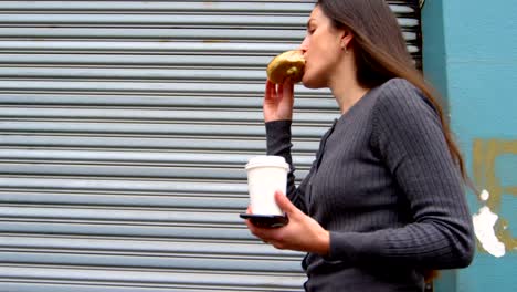 Woman-eating-donuts-while-walking-on-street-4k