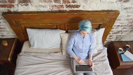 Hipster-mujer-sentada-en-la-cama-y-trabajando-en-ordenador-portátil