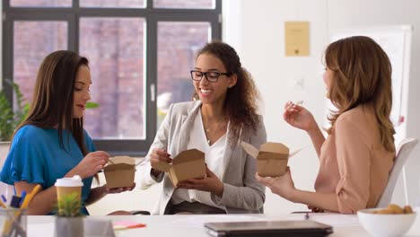 happy-businesswomen-eating-take-out-food-at-office