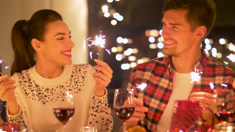 happy-friends-with-sparklers-having-christmas-dinner-at-home